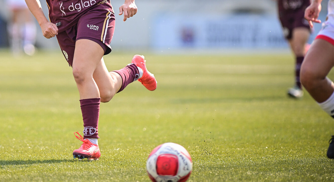 mulher prestes a chutar a bola num campo de futebol