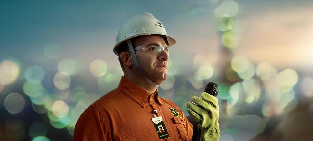 Colaborador Petrobras segurando walkie-talkie. Ele está utilizando EPIs de segurança.