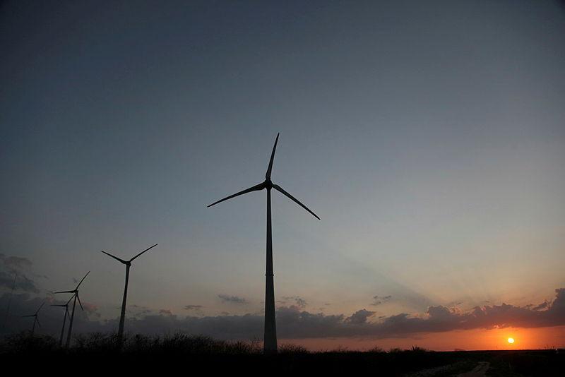 Torres de energia eólica, e ao fundo uma paisagem do por do sol.